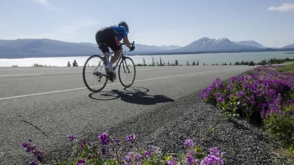 A road biker speeds down the side of a Yukon highway