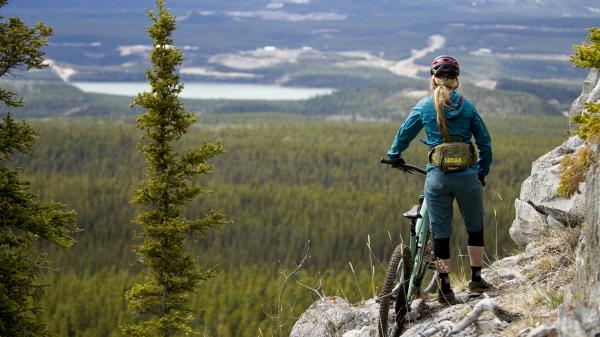 A woman looks out a view from rocky cliff  