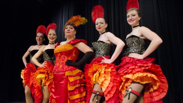 5 Gertie's dancers in orange and red can can dresses line up on stage