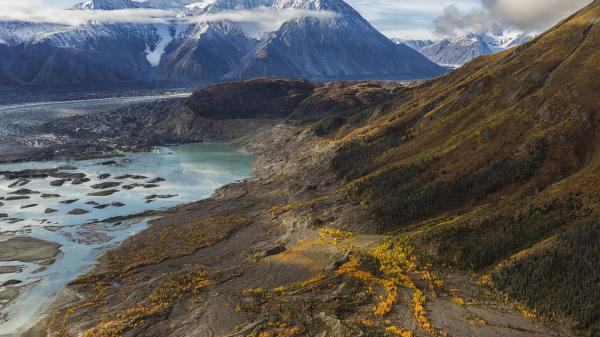 A mountainside runs into a teal lake