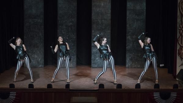 four dancers in black & white striped pants and black shirts perform on stage