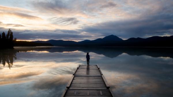A person enjoys the sunset on the dock at Squaga Lake Campground
