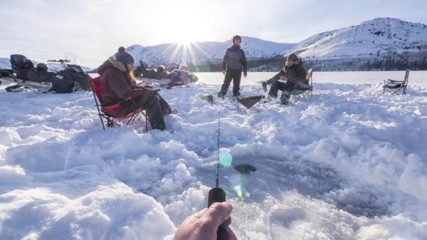 A group of people ice fishing on a Yukon lake