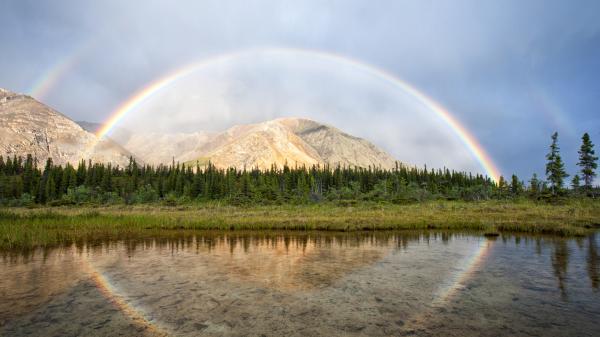 A rainbow stretches over a mountain