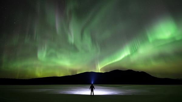 A person stands in awe under the northern lights