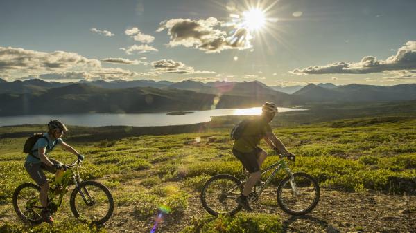 Two bikers enjoy a ride under the midnight sun near Fish Lake