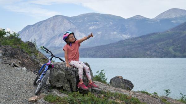 A child sits by the lake at Conrad Campground.