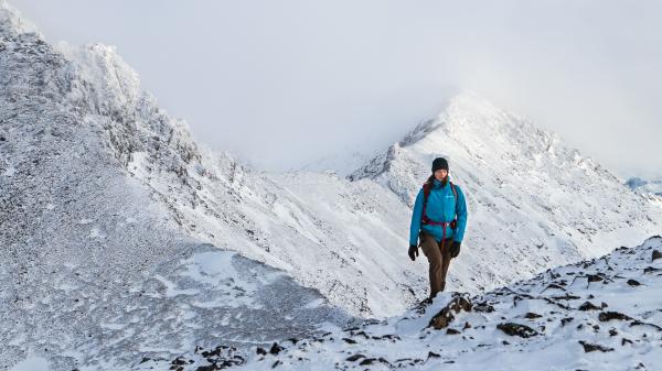 A woman walking along a snowy ridge