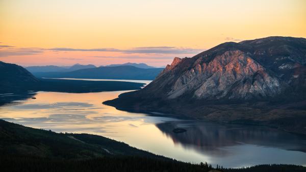 pink and orange sunset over mountains and a lake