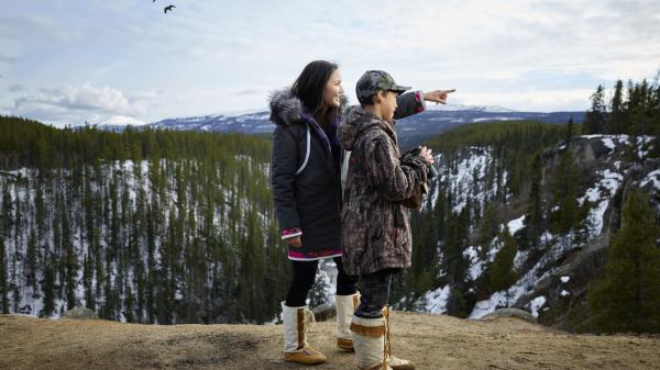 mom and son at a ridge look out with ravens flying overhead
