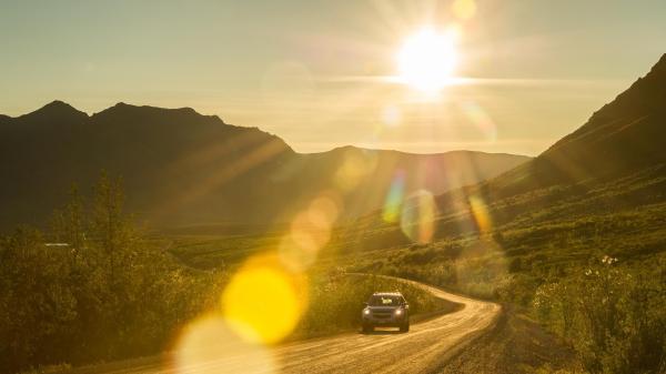 A vehicle goes down the Dempster highway under the midnight sun