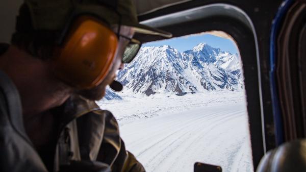 A passenger looks out the window of a flight over the ice fields of Kluane National Park and Reserve.