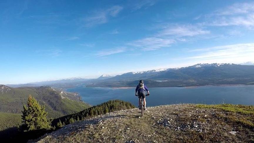 A biker enjoys the view at the top of Mount White