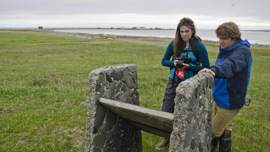 Two people read an interpretive panel on Herschel Island