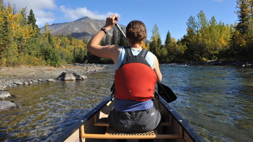 A woman paddles a canoe