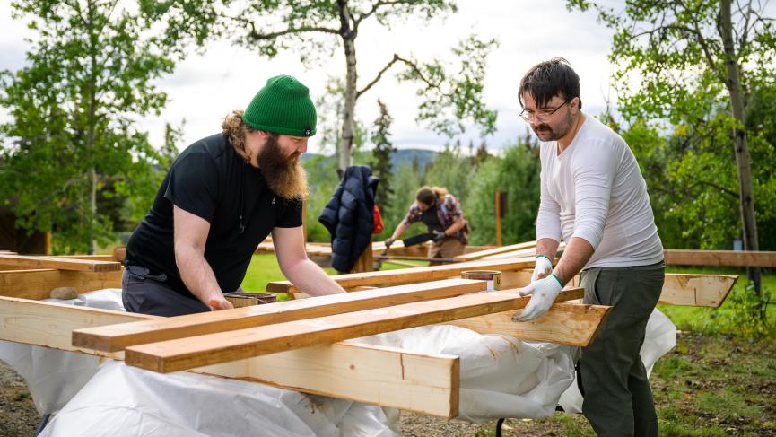 Two men work on a wood structure