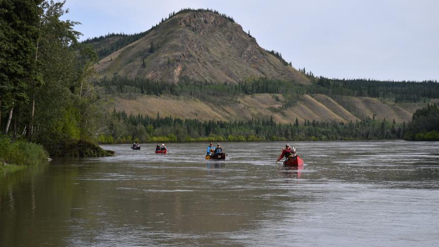4 canoes on river with mountain in background