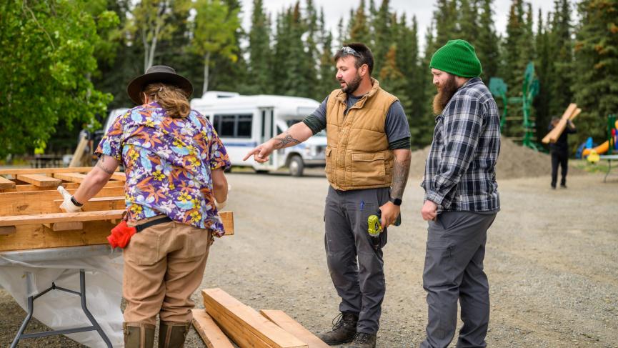 three people build a picnic table