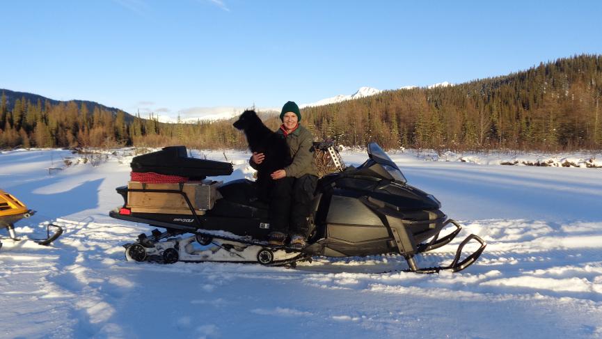 Woman with dog sitting on snowmachine