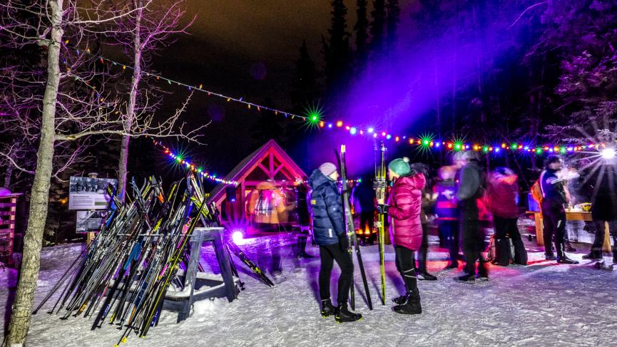 Skiers celebrating the winter solstice at night with music and lights outside Harvey’s Hut.