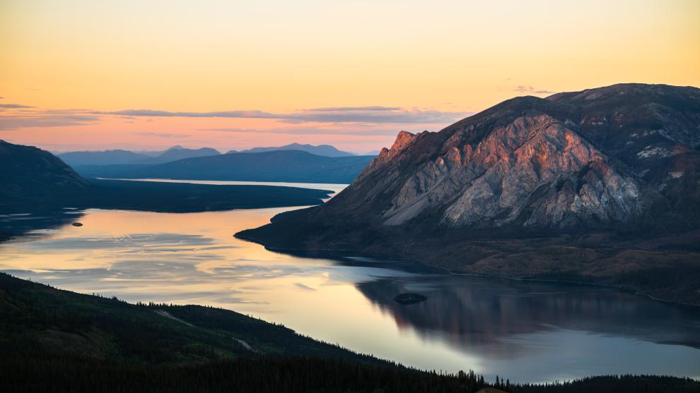 pink and orange sunset over mountains and a lake