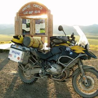 A motorcycle sits in front of the Arctic Circle sign