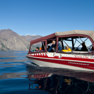 A red power boat on a big lake with a mountain in the background