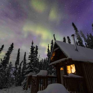 Evening winter scenery with a cabin and Aurora Borealis above
