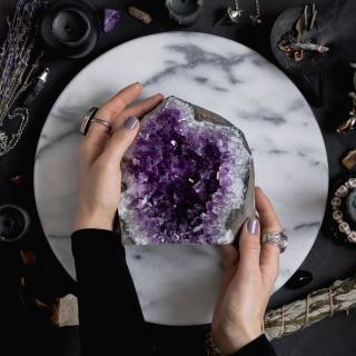 top view of women's hands holding large amethyst piece