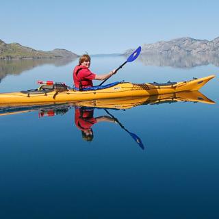 A person in a yellow kayak on a clear lake