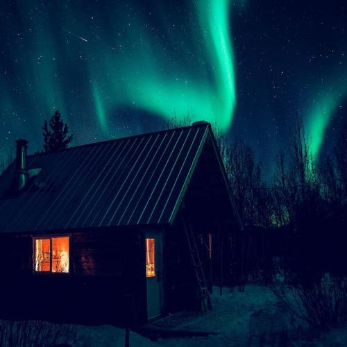 Northern lights shine above a cabin