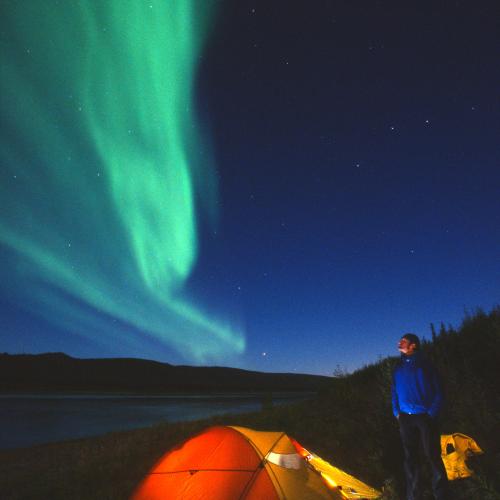 Northern lights over a glowing orange tent