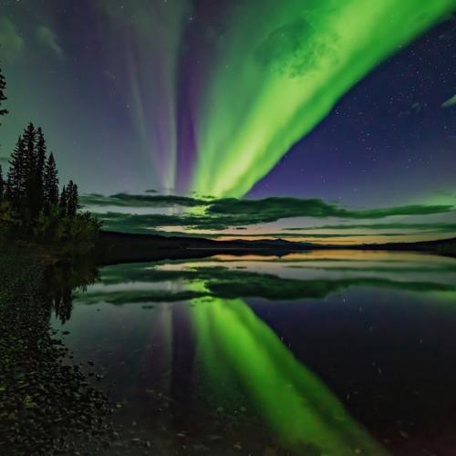 Northern lights flicker across a still Yukon lake