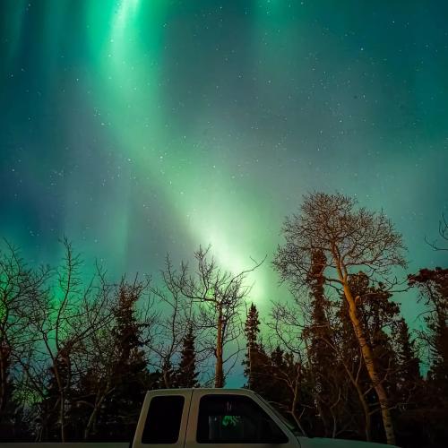 Northern lights dance above a parked vehicle