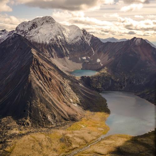 Two bright teal lakes in the bowl of a large mountain.