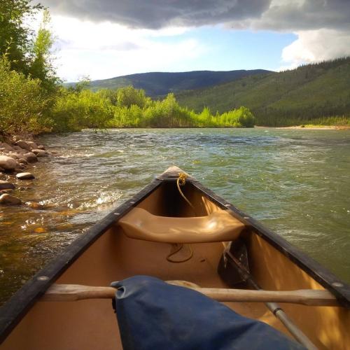 A canoe sits on the shores of a river under the sunshine
