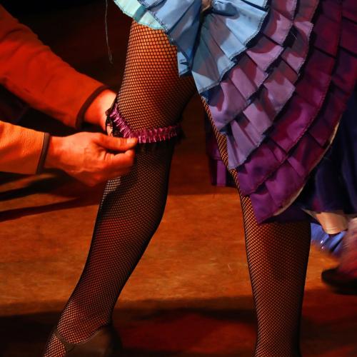 A can can dancer gets a garter put on her leg