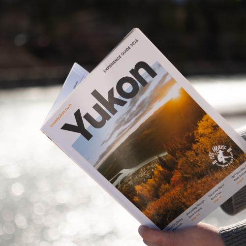 A person reads the experience guide by the river 