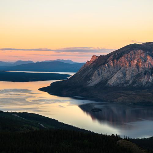 pink and orange sunset over mountains and a lake