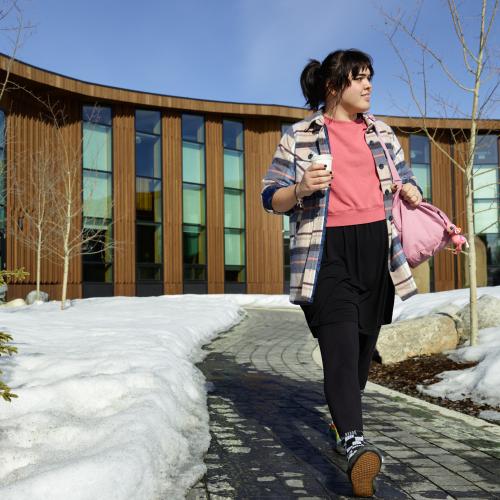 A woman walks with a coffee away from her place of work