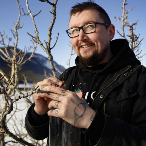 Blake on the shores of Bennet Lake, taking buds off a tree
