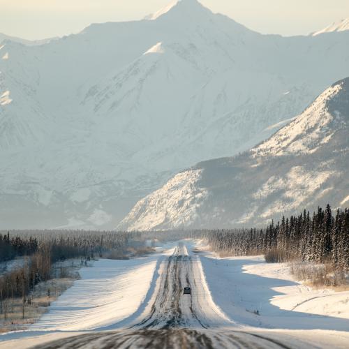 Winter road trip through snow-covered Yukon highway with scenic mountain views.