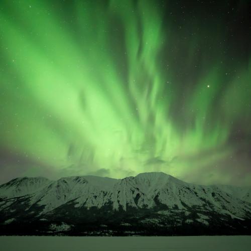Northern lights above a mountain in winter.