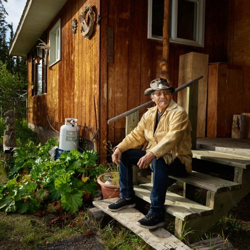Dennis Shorty sitting on the steps of his cabin