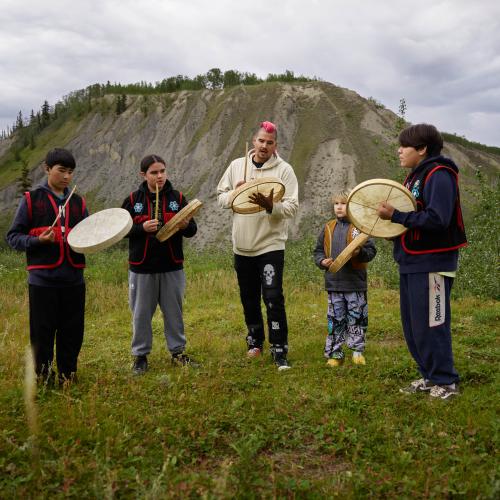 Derrick standing playing the drum with the group. 