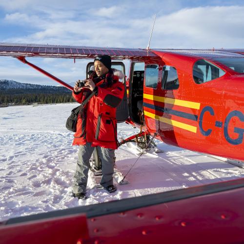 A person standing next to a flight seeing tour plane.