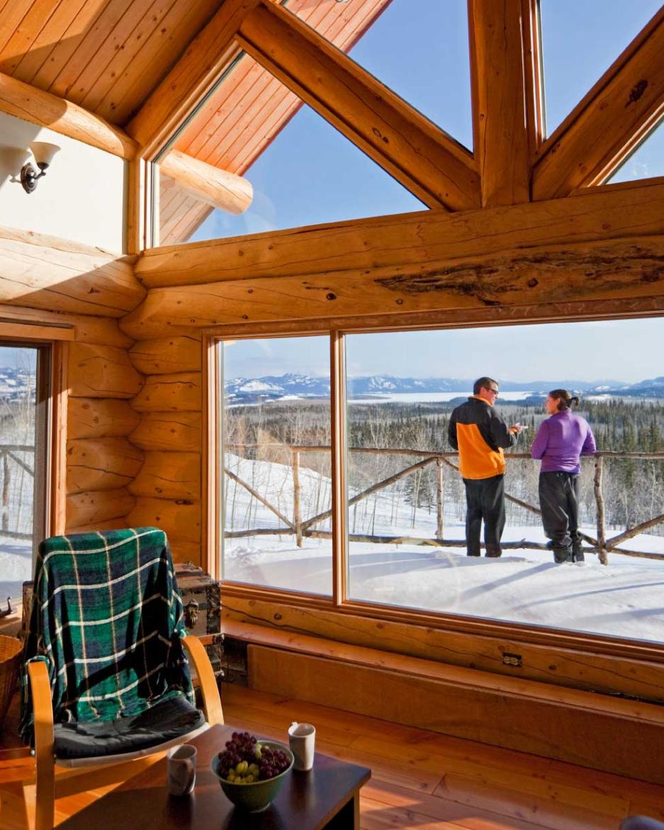 A couple enjoys the view from their cozy lodge