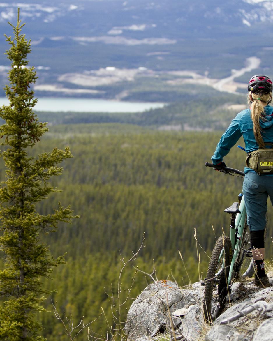 A woman looks out a view from rocky cliff  