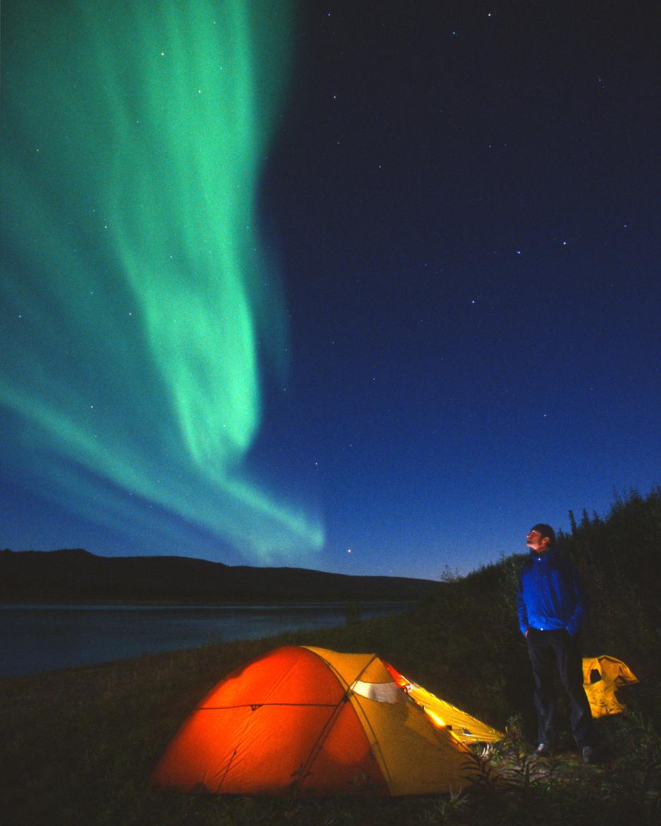 Northern lights over a glowing orange tent