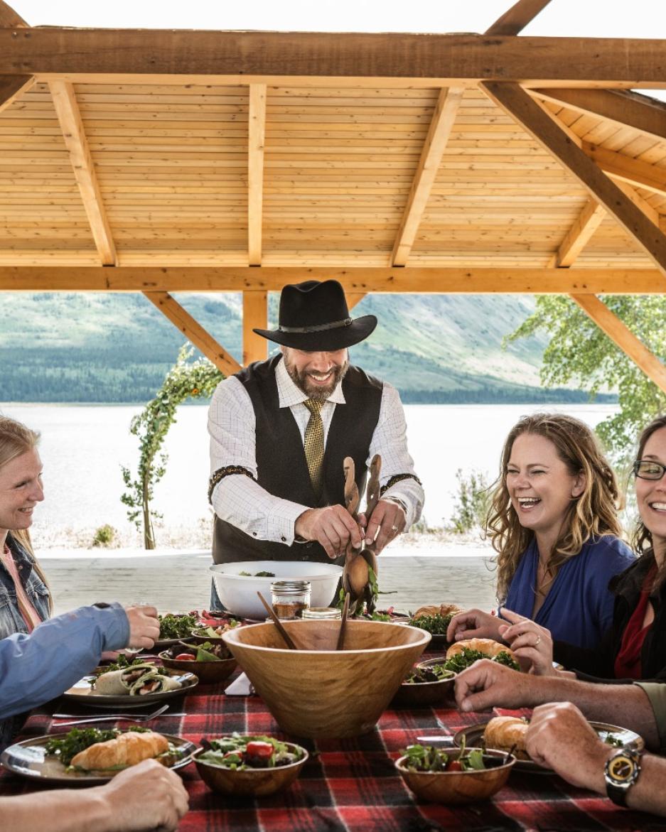 A group of people are dining next to a lake. 